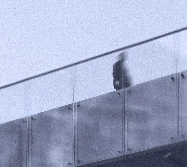 A person walking behind the glass balustrade of a modern office building